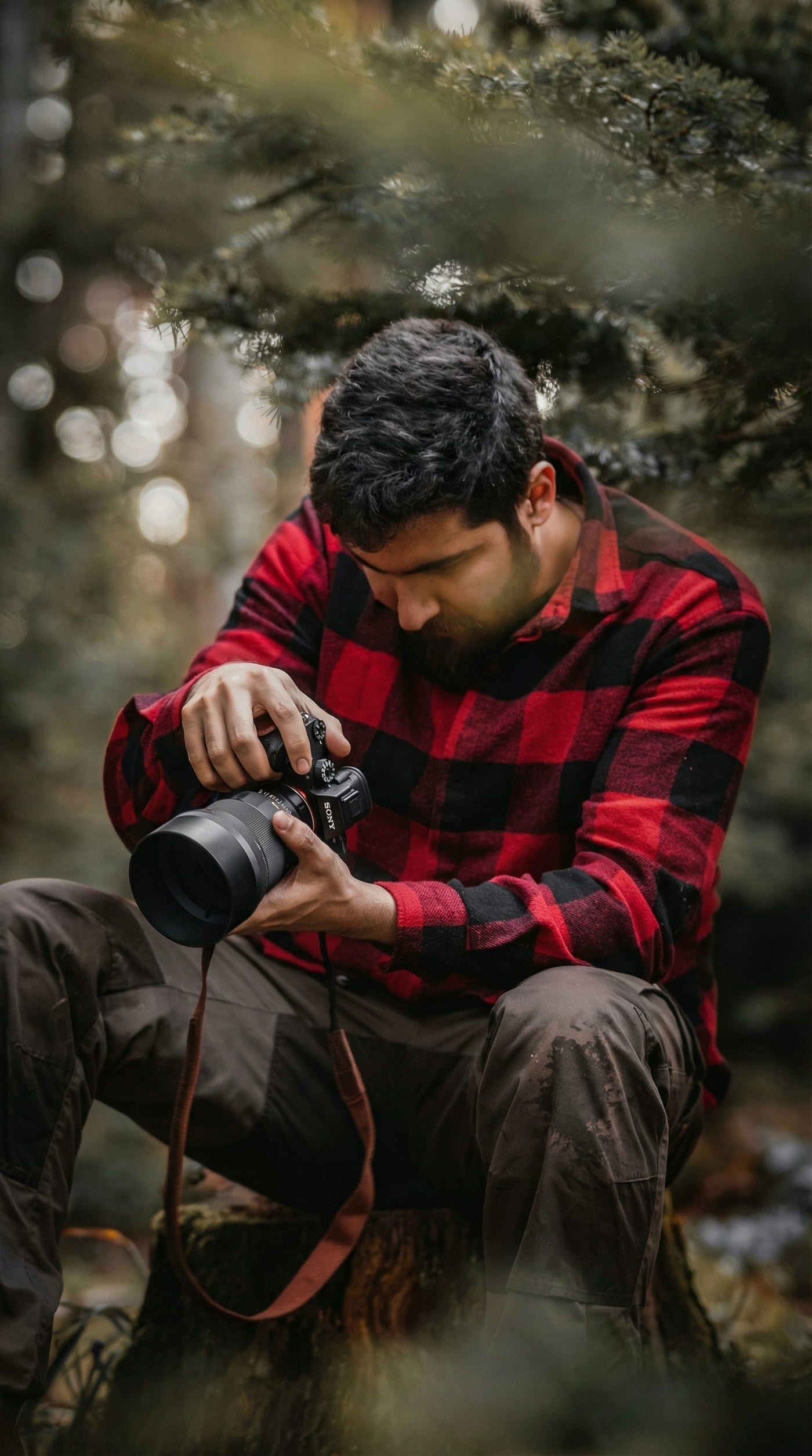 A photographer reviewing an open hardcover portfolio book on a desk with printed photographs arranged nearby