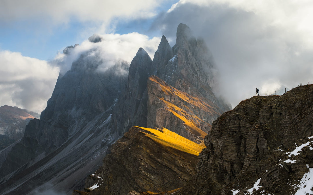 Morning sun on the grass shelf of the Seceda ridge, with the Odle peaks in cloud behind