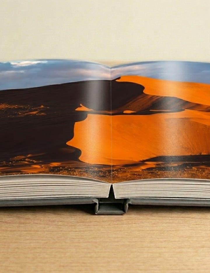 A photographer reviewing printed photo book spreads on a desk
