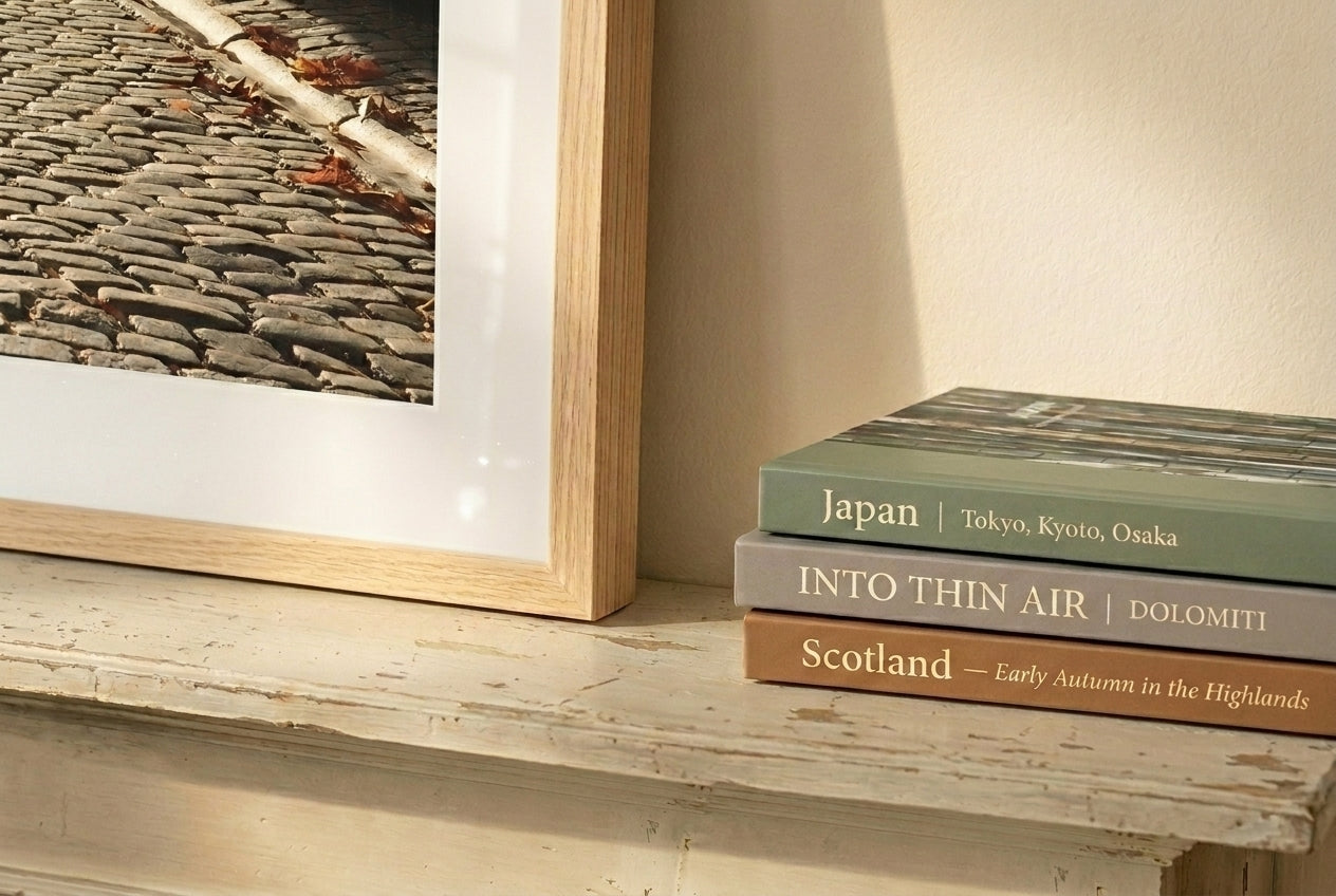 Stack of books on a shelf next to a framed picture