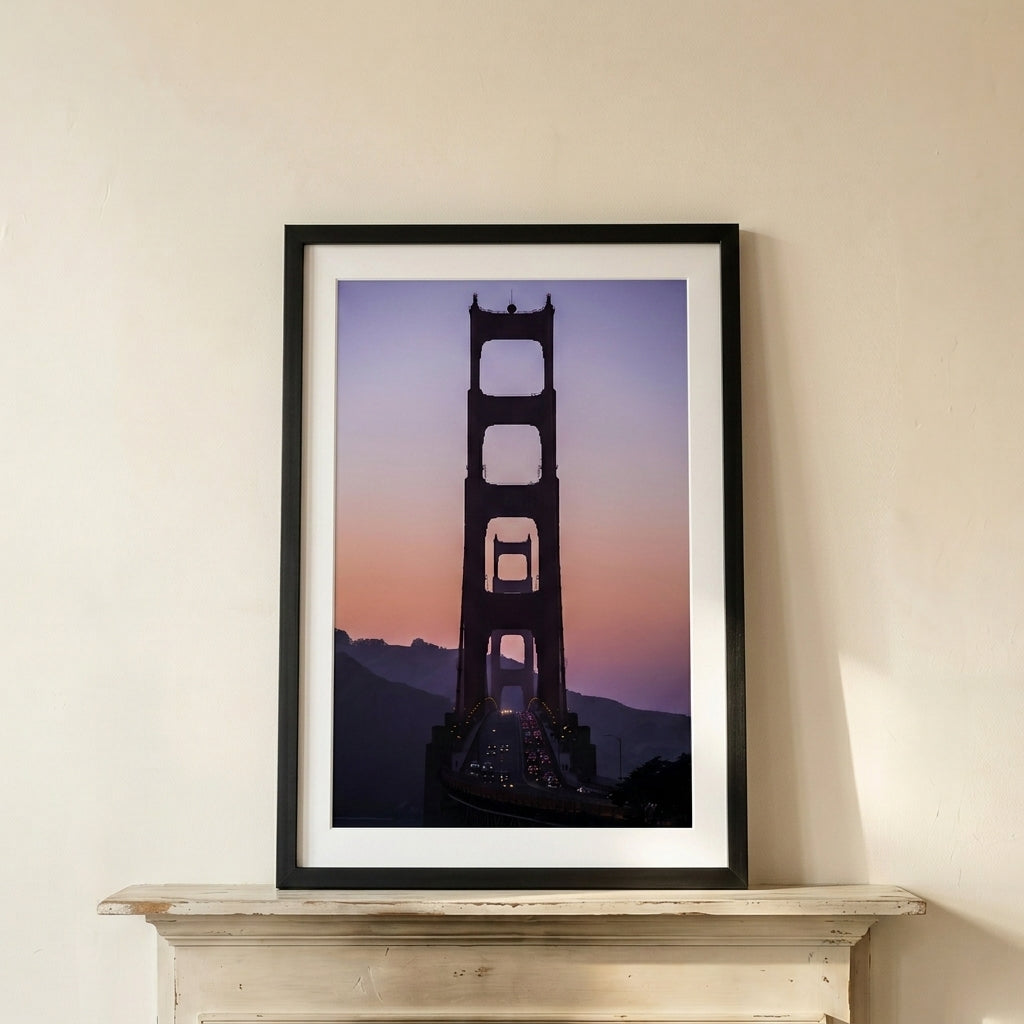 Framed artwork of the Golden Gate Bridge silhouette against a purple sky on a white wall.