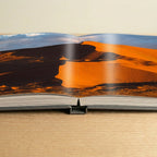Open book showing a landscape with mountains and sky.